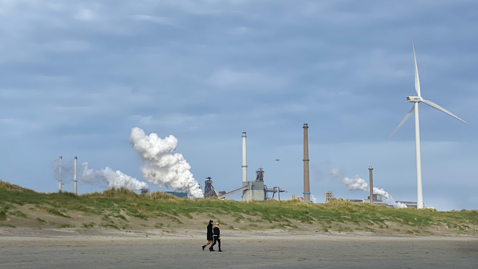 Foto CO2-beprijzing: uitzicht op een fabriek met een windmolen ernaast